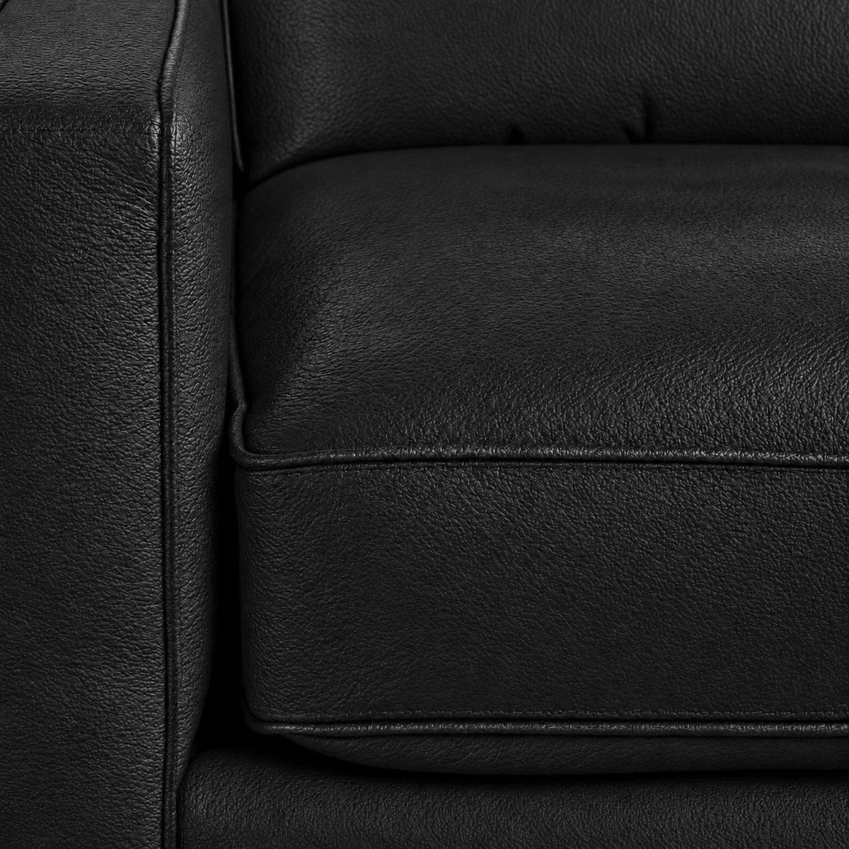 Close-up of the City Leather Loveseat - Black showing the leather grain, piped seat cushion and matching upholstered arm