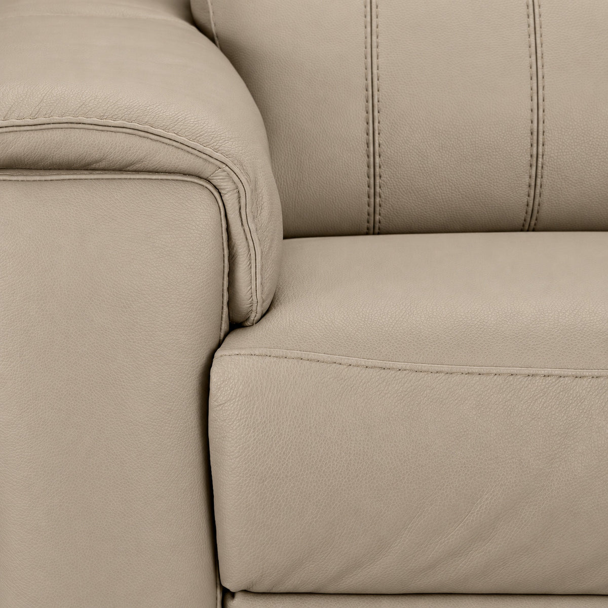 Detailed view of the tan leather grain, stitching, padded arm and seat cushion