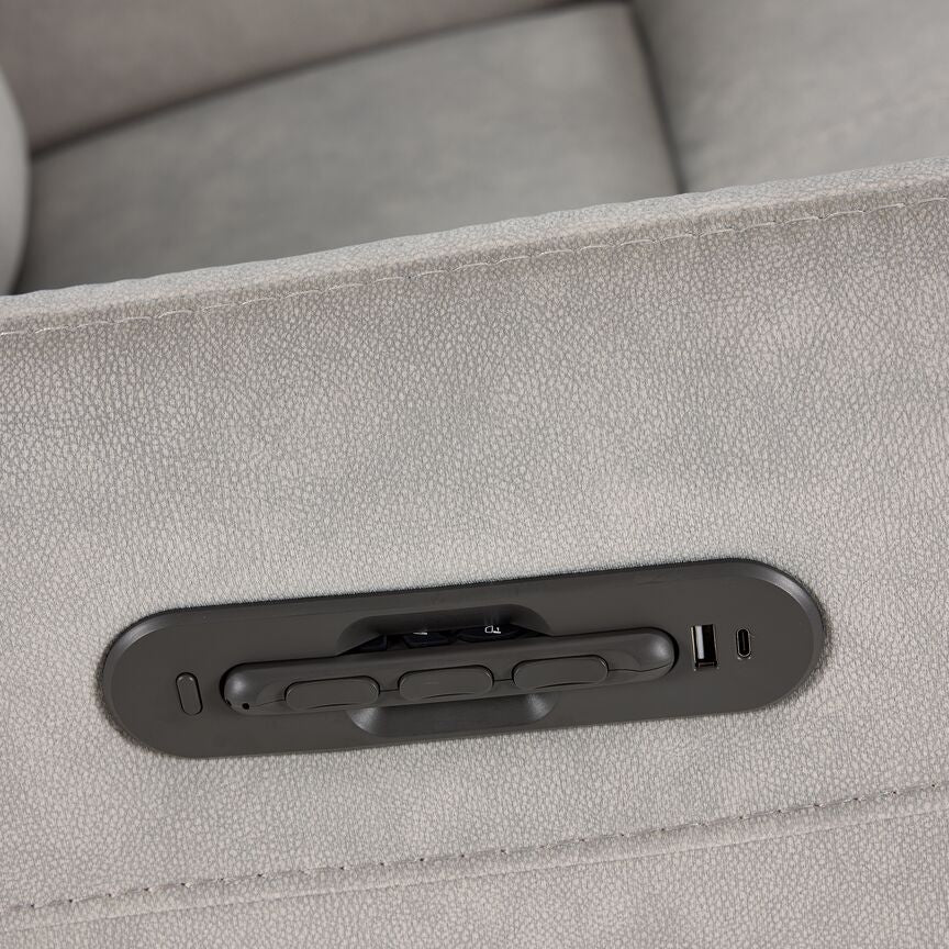 Close-up of Chase Power Rocker Recliner armrest with remote stored in its dock beside USB charging ports