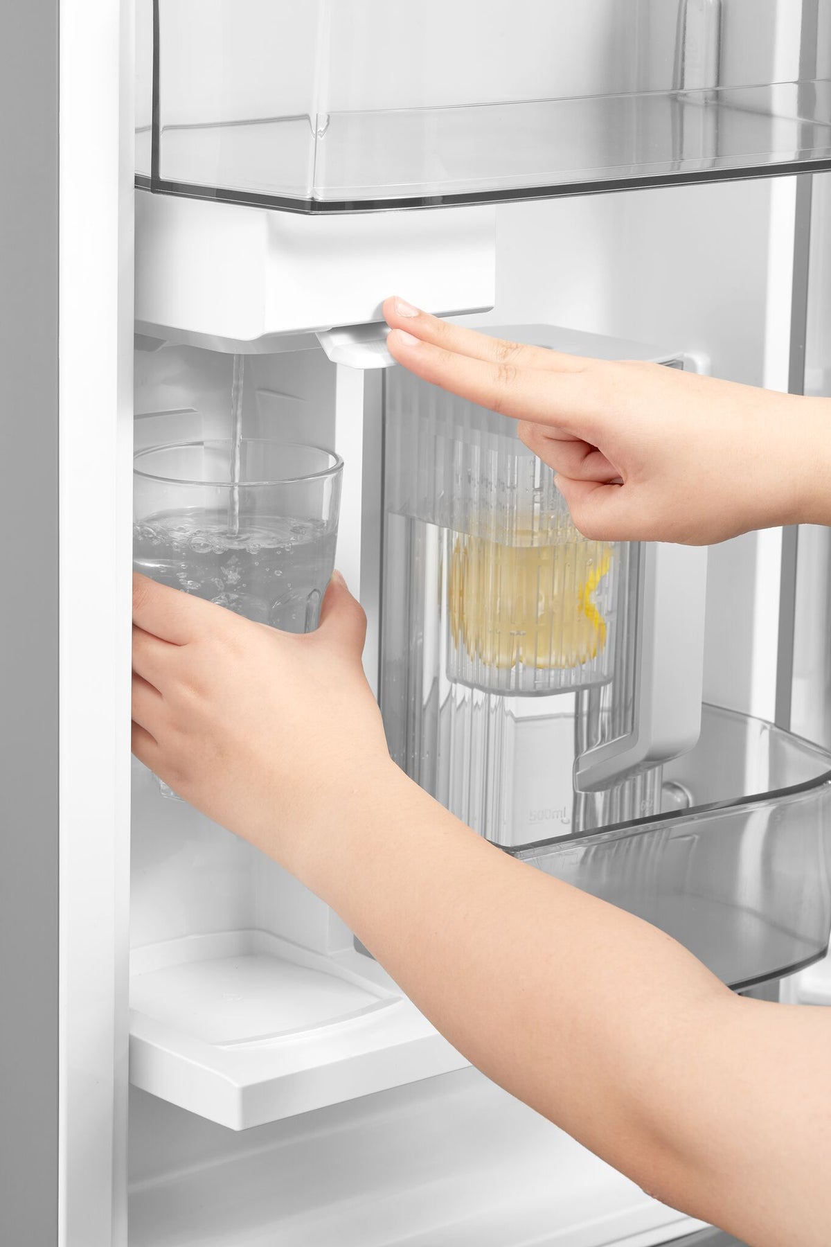Internal water dispenser filling a drinking glass beside the removable pitcher