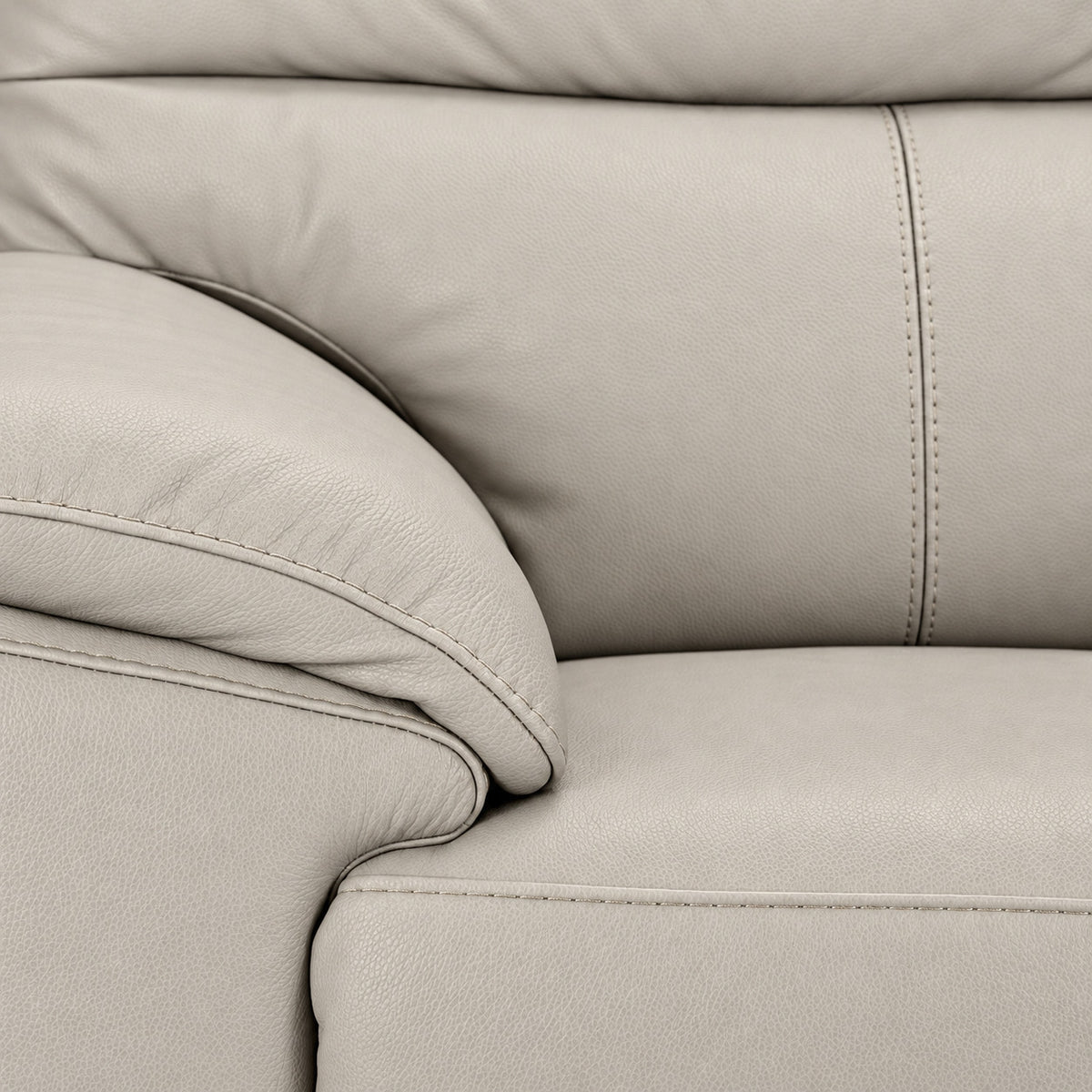 Close-up of cream leather upholstery, stitching, cushioned arm and seat