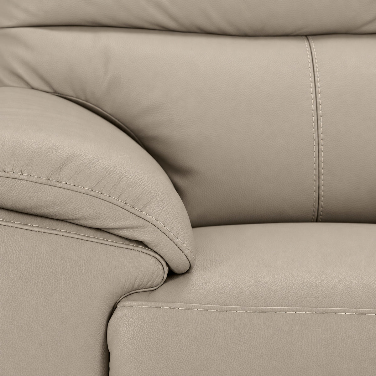 Detailed view of tan leather grain, stitching, cushioned arm and seat
