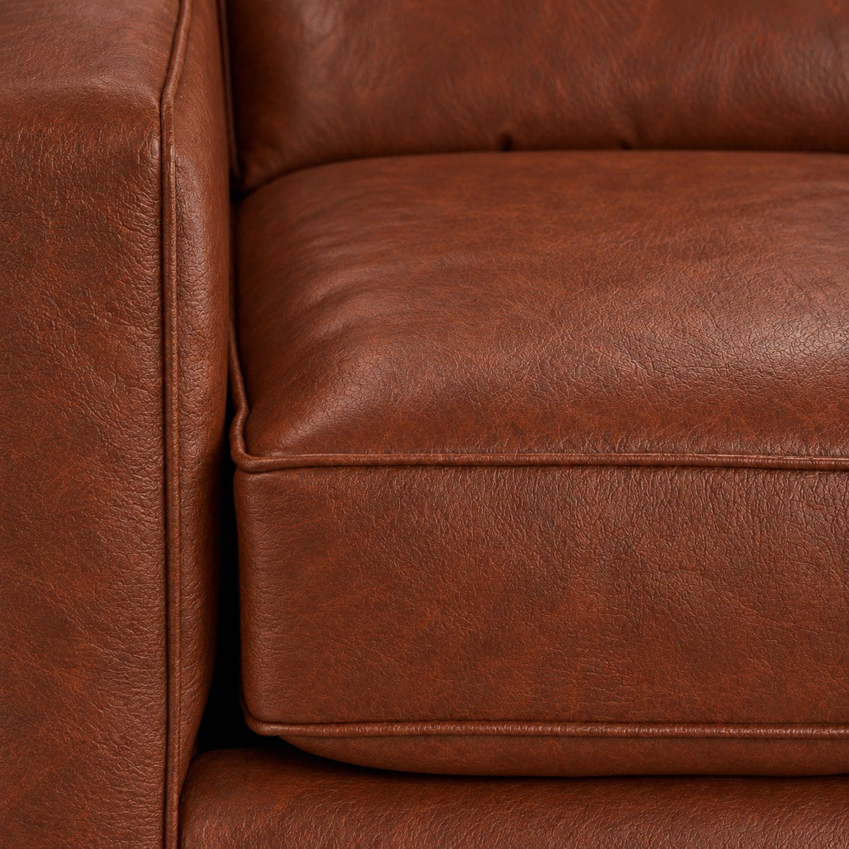 Close-up of the City Leather Sofa - Brown showing the leather grain, piped seat cushion and matching upholstered arm