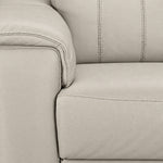 Close-up of cream leather grain and stitching along the padded arm and seat cushion