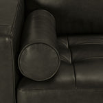 Close-up of charcoal leather upholstery with cylindrical bolster pillow, stitched edges and tufted seat cushion